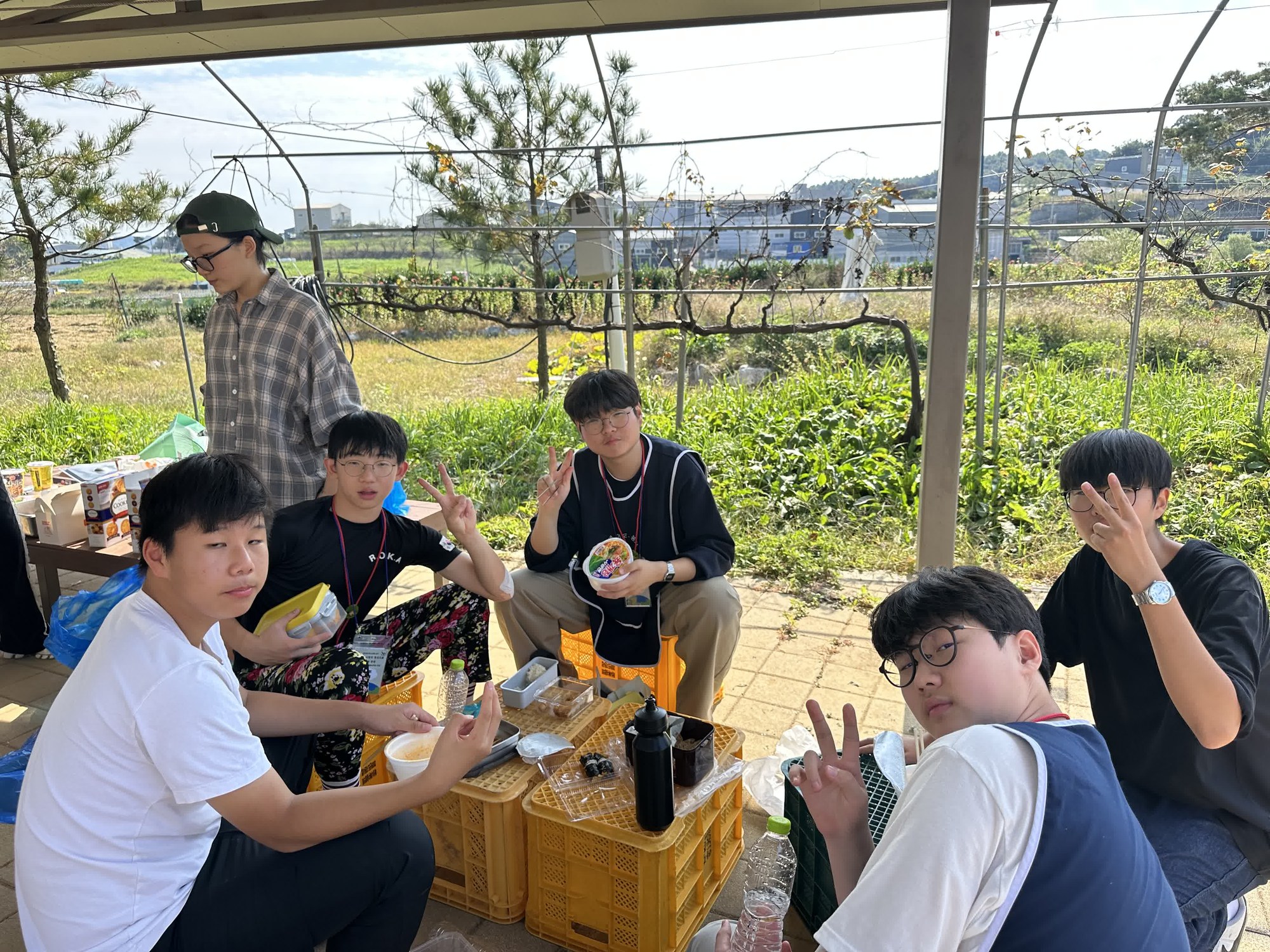 노란 상자를 식탁 삼아 둘러앉아 간식을 먹는 청소년들