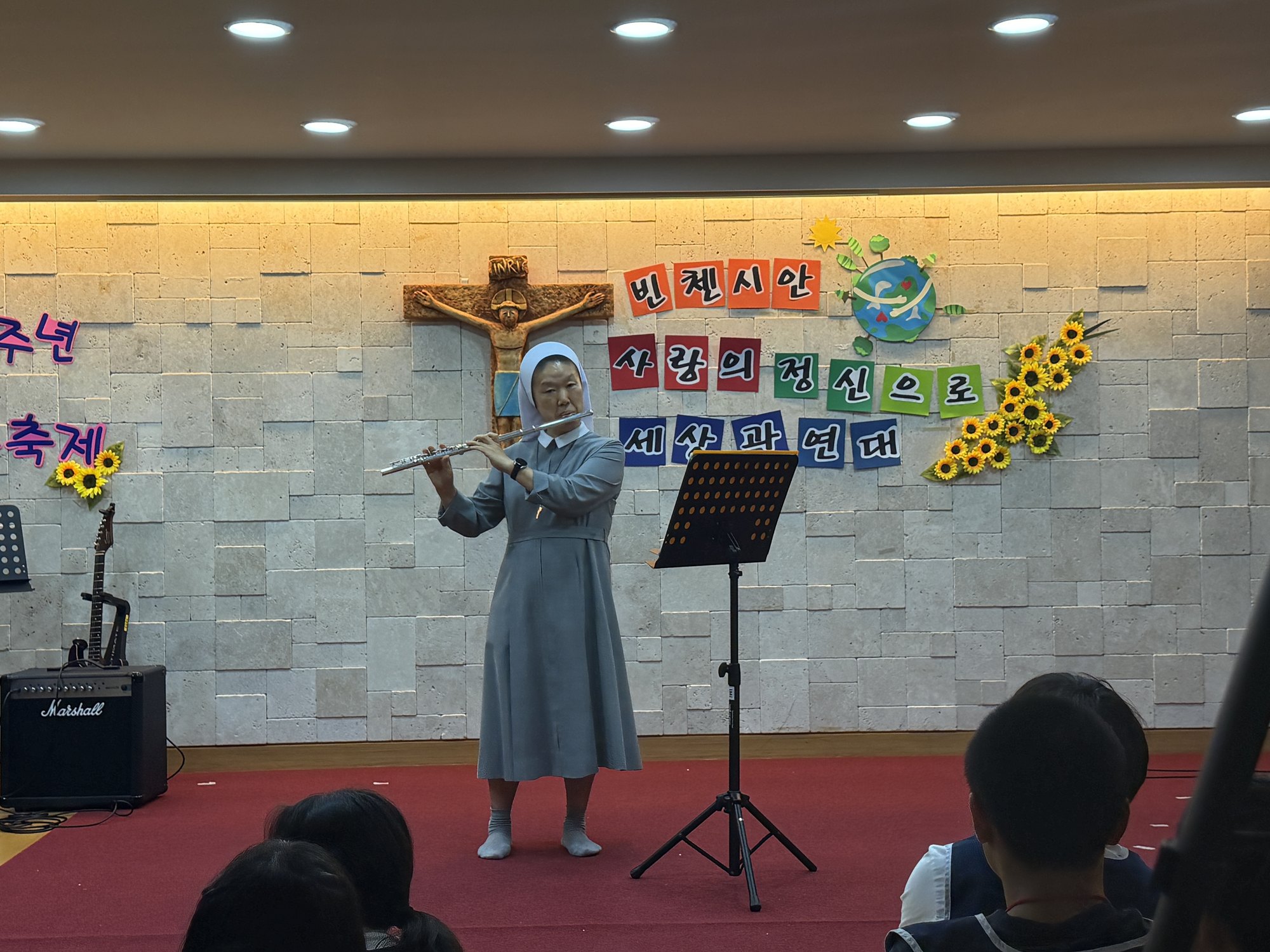 해바라기로 꾸민 무대에서 플루트를 연주하는 수녀님