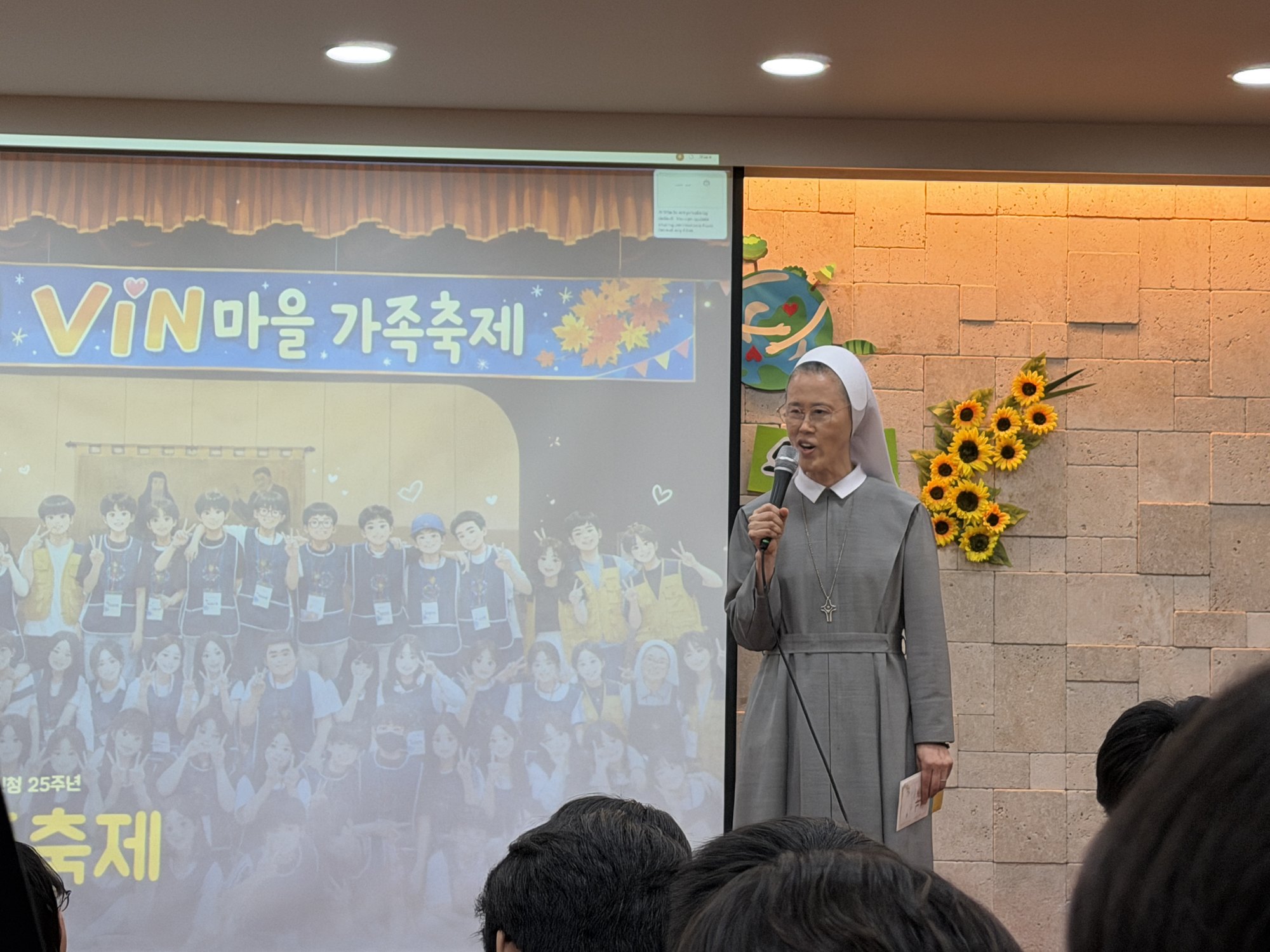 ‘VIN마을 가족축제’ 화면 앞에서 마이크를 들고 인사하는 수녀님