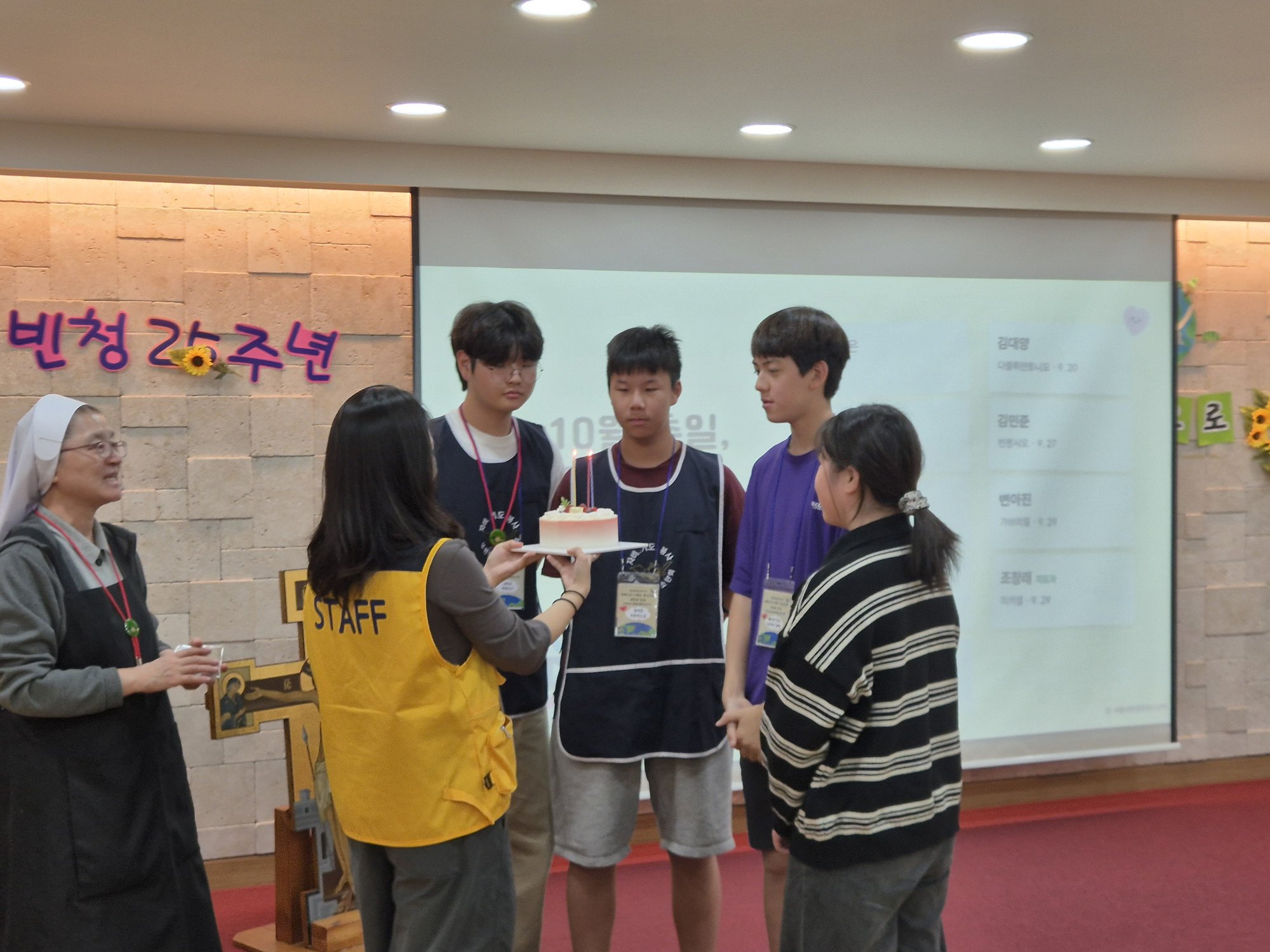 케이크를 든 선생님과 축일 친구들을 바라보며 웃는 수녀님