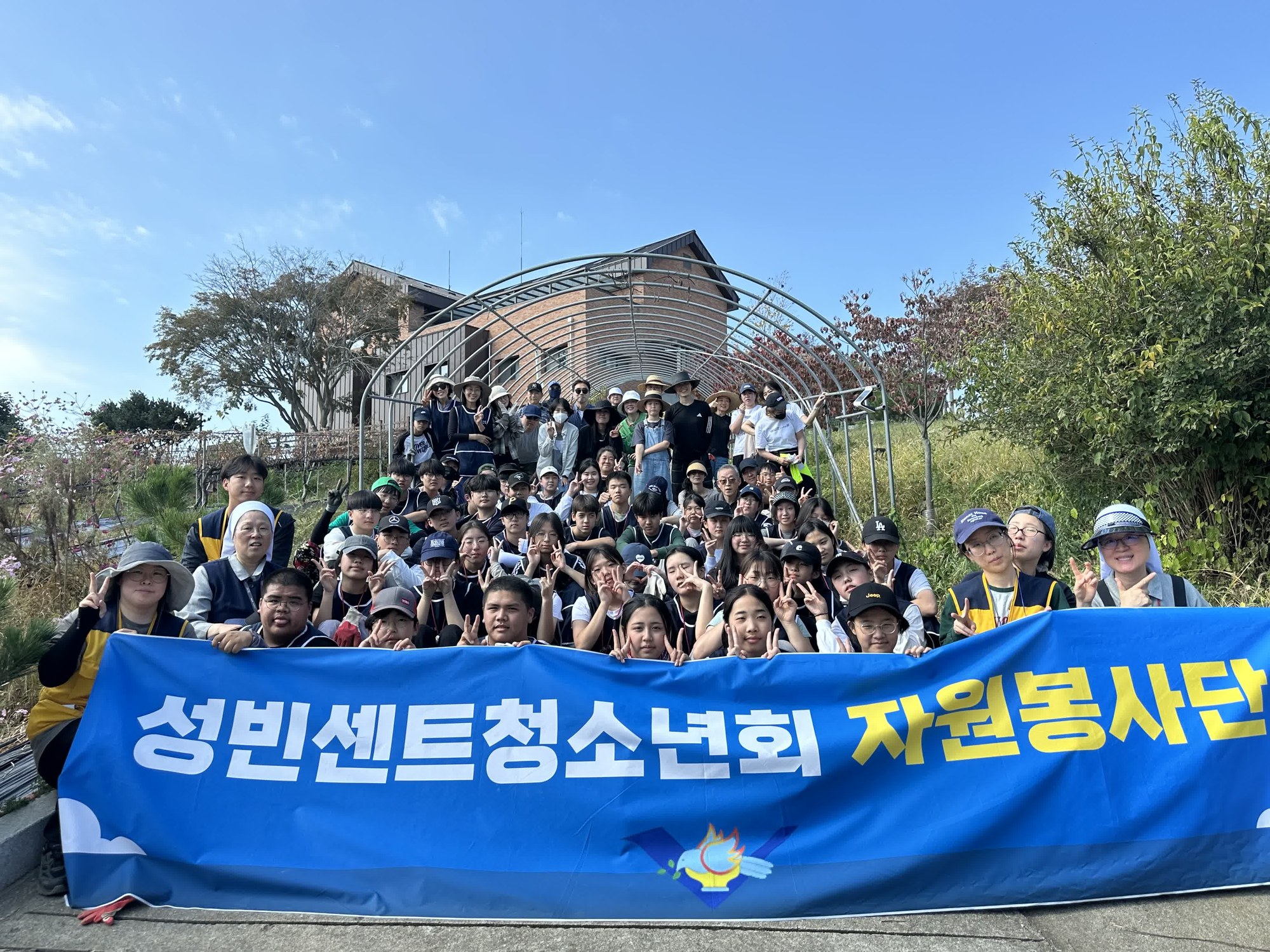파란 가을 하늘 아래 ‘성빈센트청소년회 자원봉사단’ 현수막을 앞에 두고 계단에 모여 찍은 단체사진
