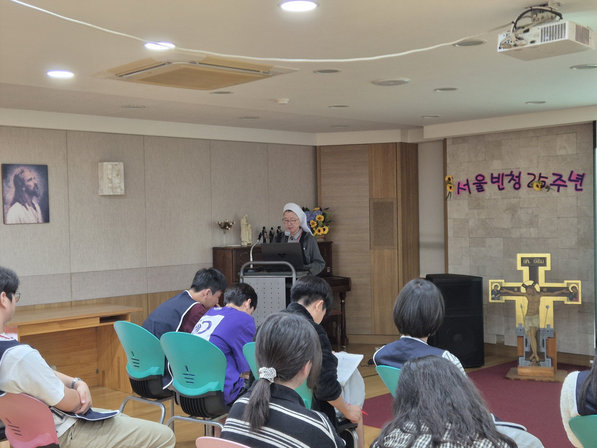 발표대 앞의 수녀님과 이야기를 듣는 친구들