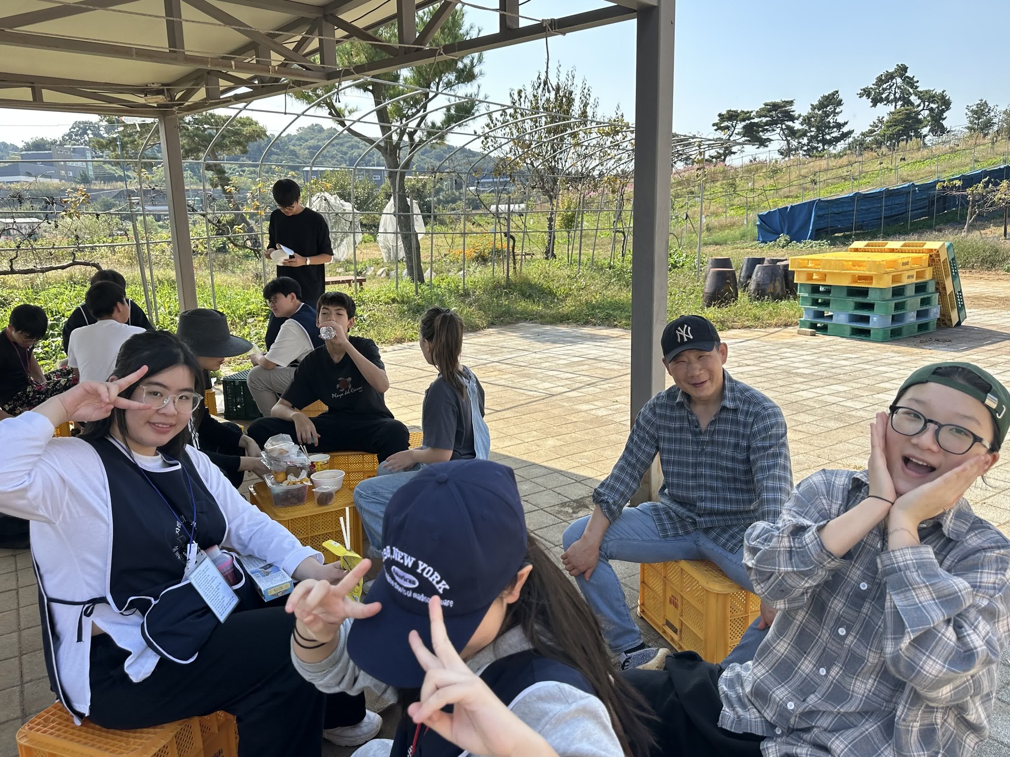 지붕 아래에서 간식을 먹다 카메라를 보고 브이를 그리며 웃는 사람들