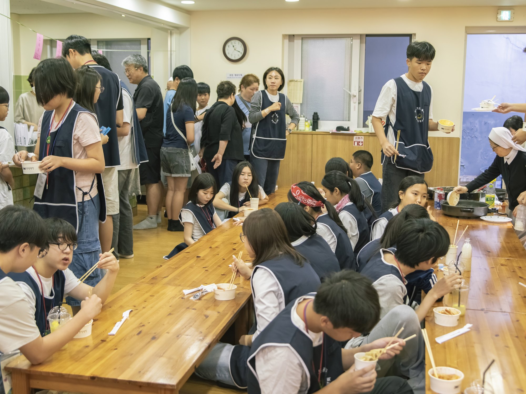 긴 식탁에 둘러앉아 함께 음식을 먹는 빈청 청소년들