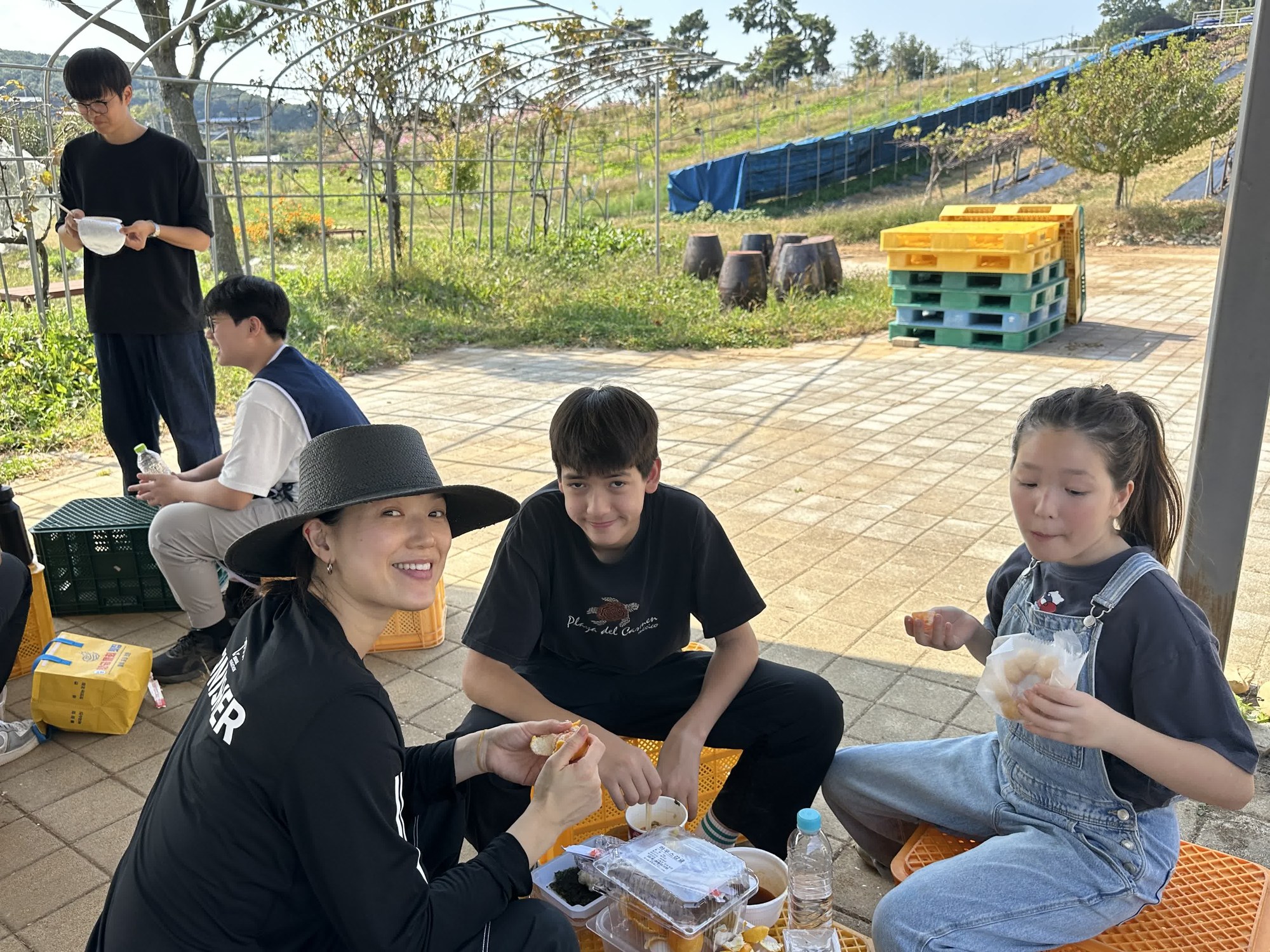 상자에 걸터앉아 간식을 나눠 먹으며 웃는 세 사람